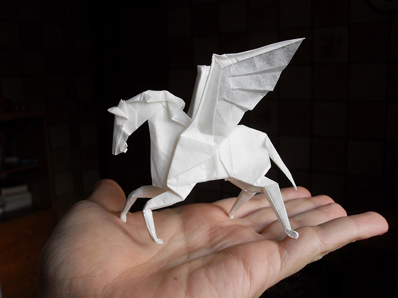 A paper pegasus standing on a person's hand