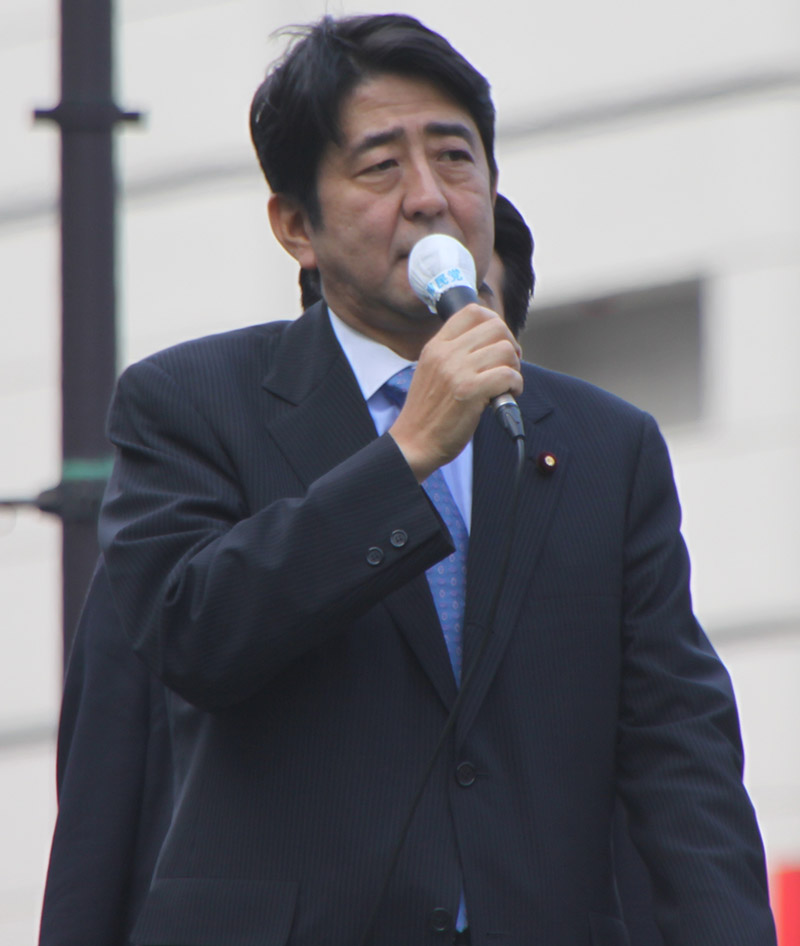 Japanese president shinzo abe talking on a microphone