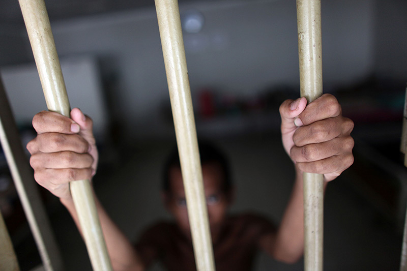 man with hands on prison bars