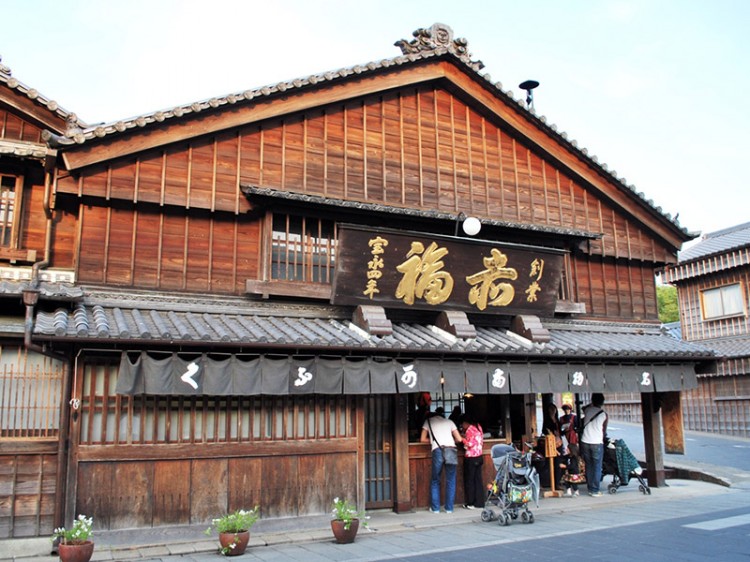 A wooden Japanese building with a short curtain hanging over its entryway