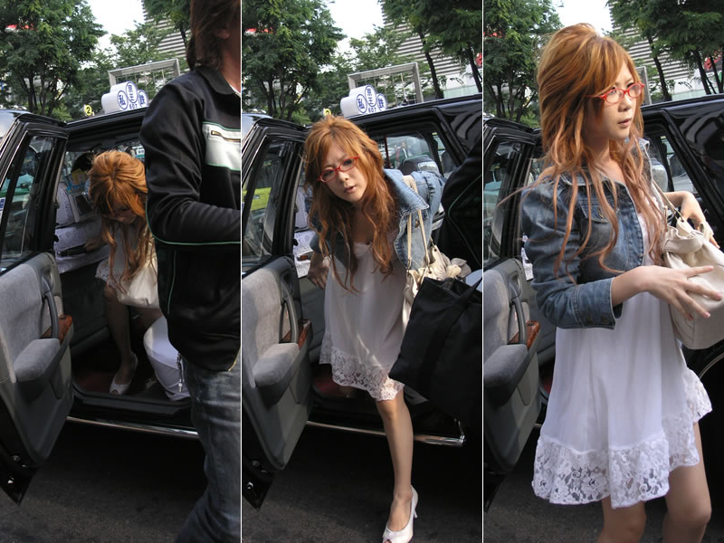 A woman with red glasses getting out of a taxi