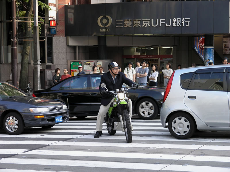 A man in a suit and glasses on a motorbike