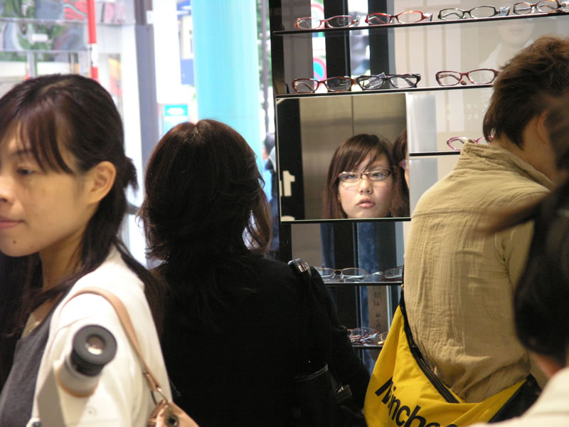 A woman looking in the mirror of a glasses shop