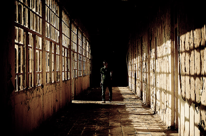 man standing alone in a strangely lit hallway