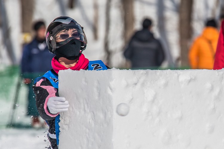 A Yukigassen player hurling a snowball from behind cover