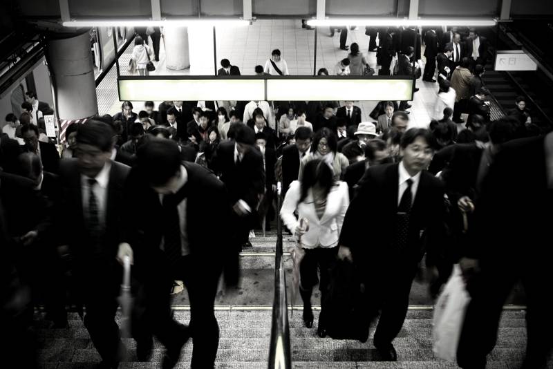 japanese commuters walking up crowded staircase in tokyo train station