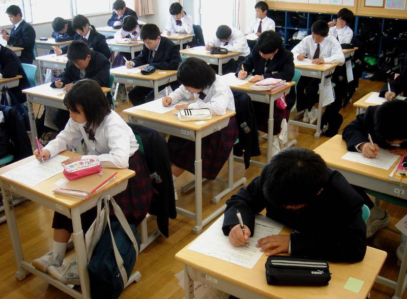 hardworking japanese students writing in seventh grade classroom
