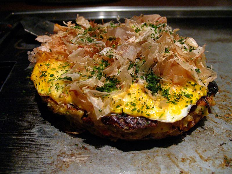 Katsuobushi fermented fish flakes on top of okonomiyaki while cooking