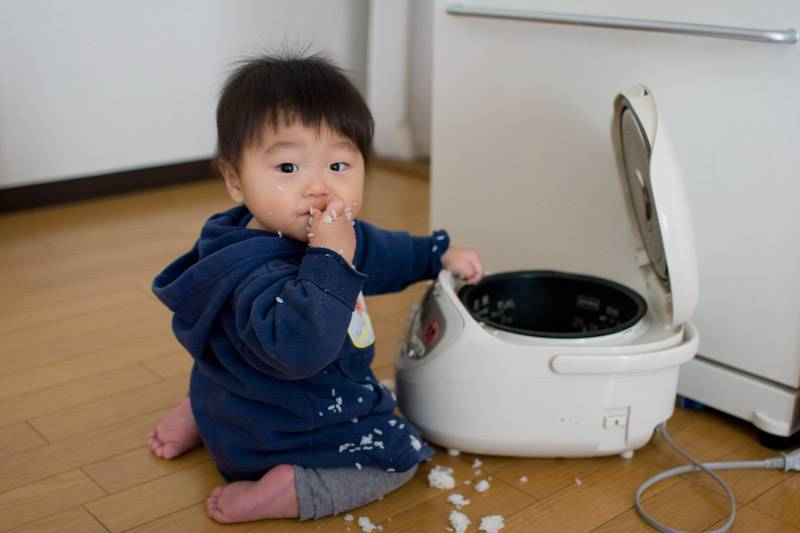 A young boy eating rice from the rice cooker