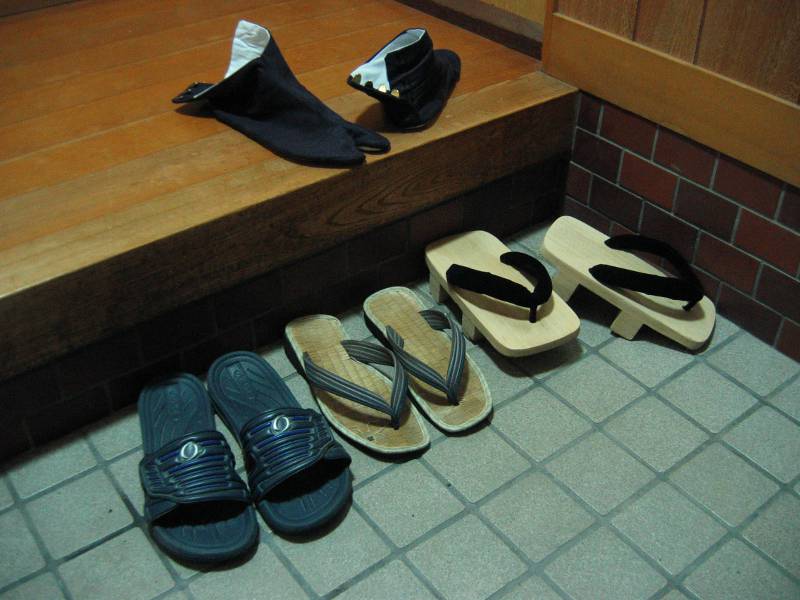 Slippers and geta in an entryway with tabi socks on the step up