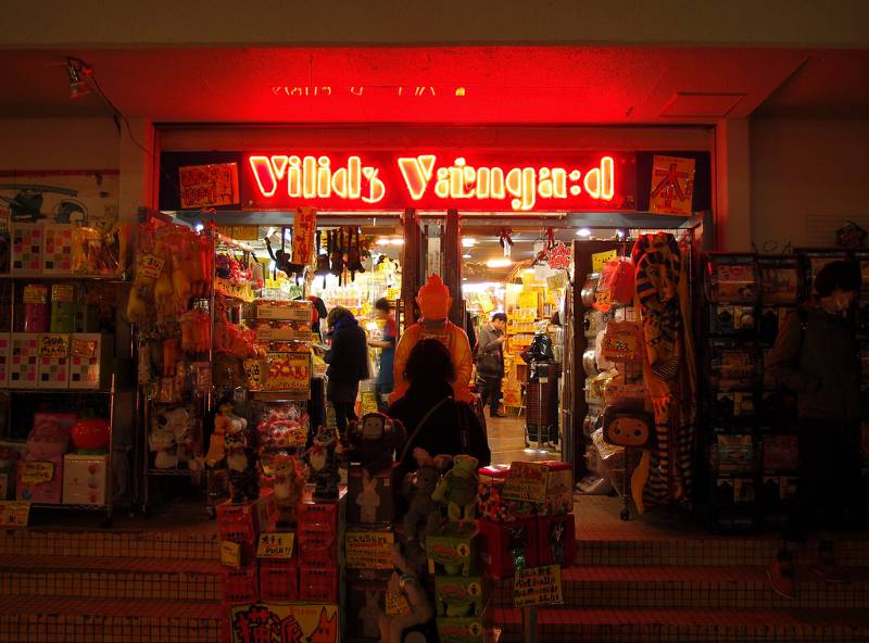 A Village Vanguard storefront at night with the neon shop sign lit up