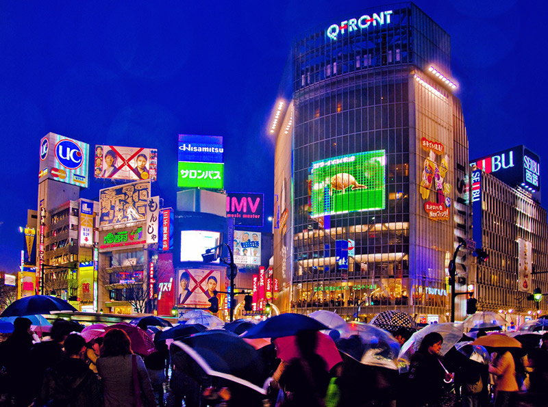 Pedestrians crossing the street during a rainy evening in Shibuya