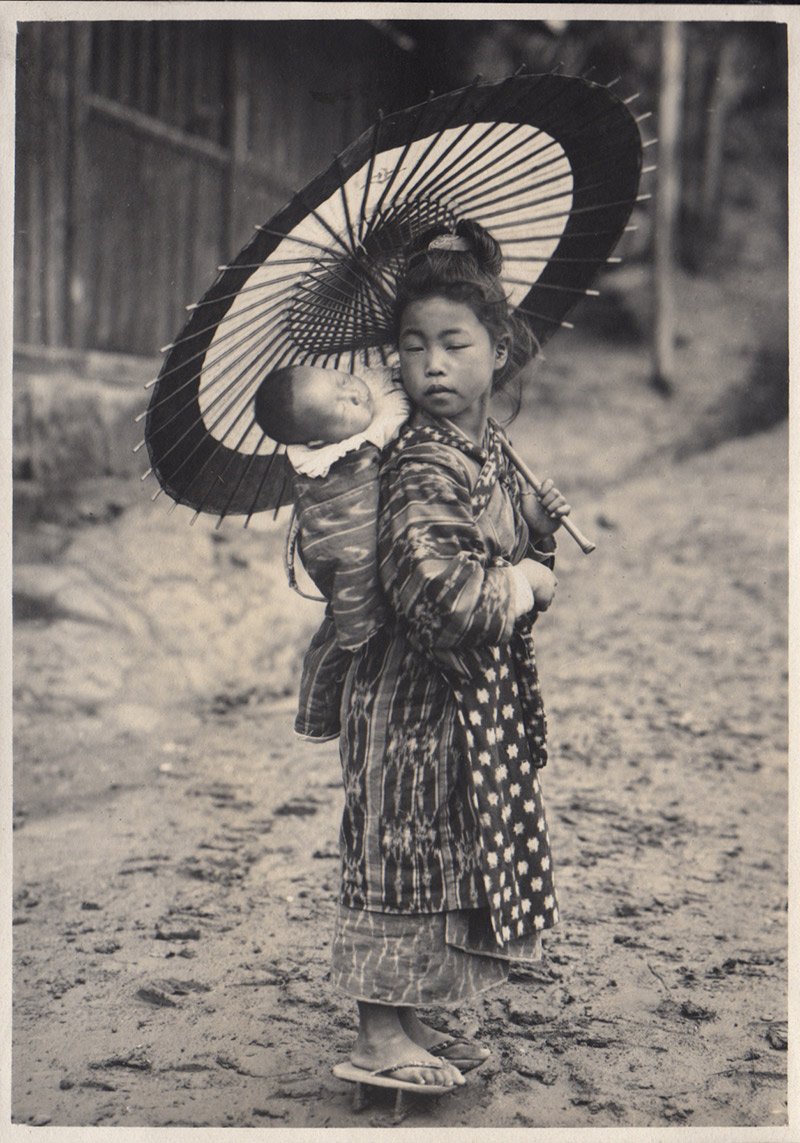 black and white photograph of girl with umbrella with baby