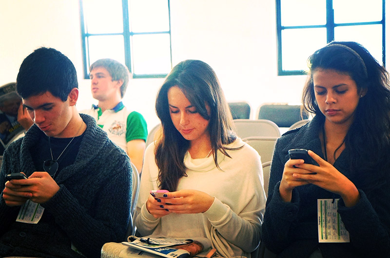 teenagers sitting and using their smartphones