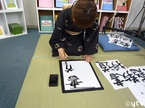 woman kneeling practicing kanji