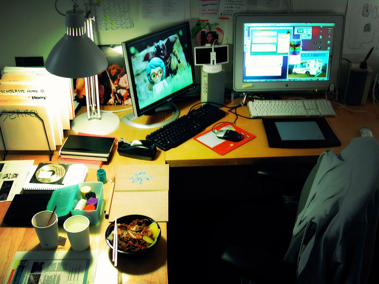 a workspace with two monitors and some food