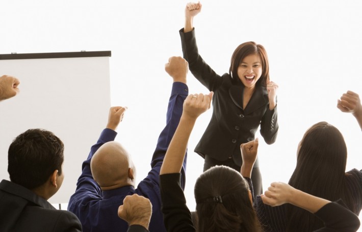 People in a meeting holding their fists up in the air