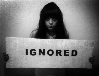 A girl holding an "IGNORED" sign