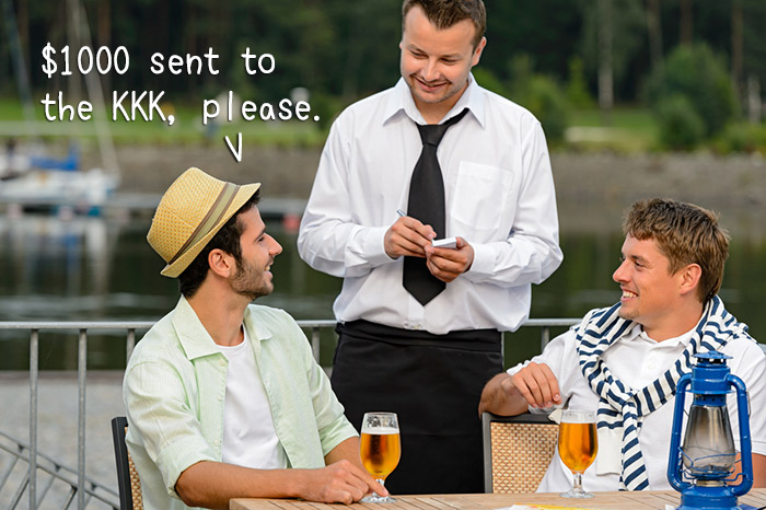 Two men sitting at a table, speaking to a waiter, with one of them saying, ‘1000 dollars sent to the KKK, please'