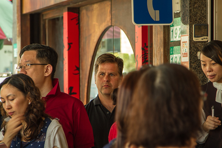 white male standing under a phone sign in taiwan