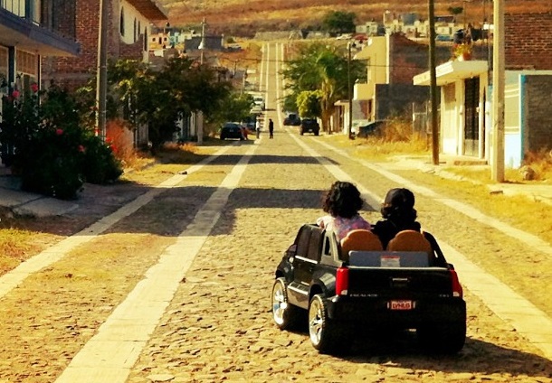 children riding in toy car