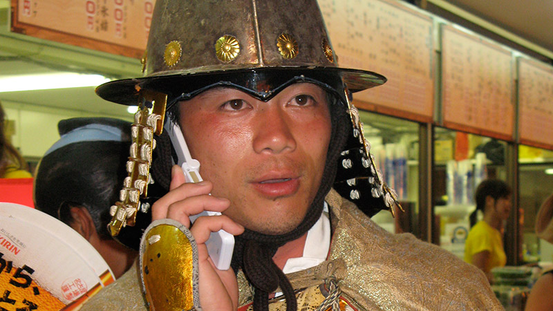 Man dressed like a Japanese official talkin on a caell phone