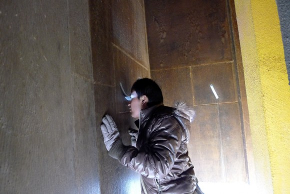 man looking through slit in wall