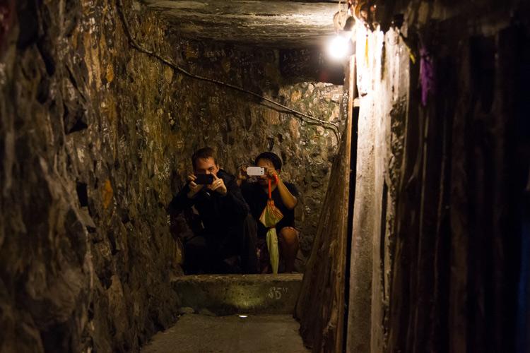 two people with cameras crouching in a tunnel in jiufen