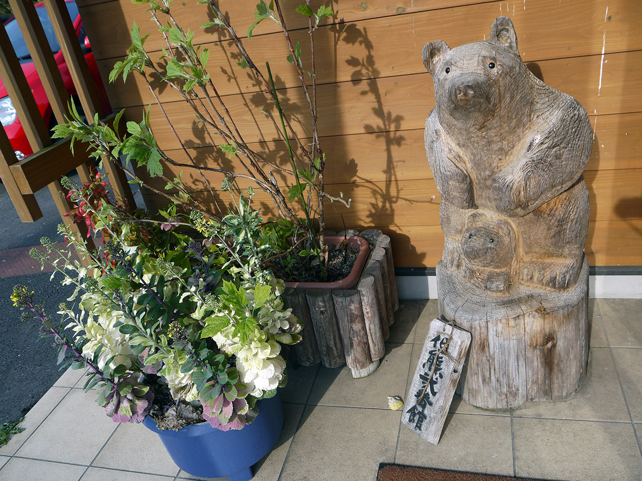 wooden bear statue next to some plants