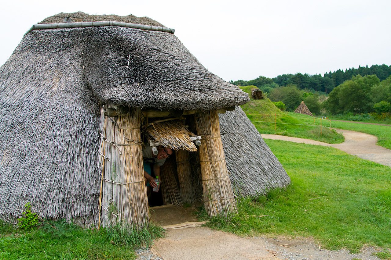 man poking head out from inside japanese historic hut