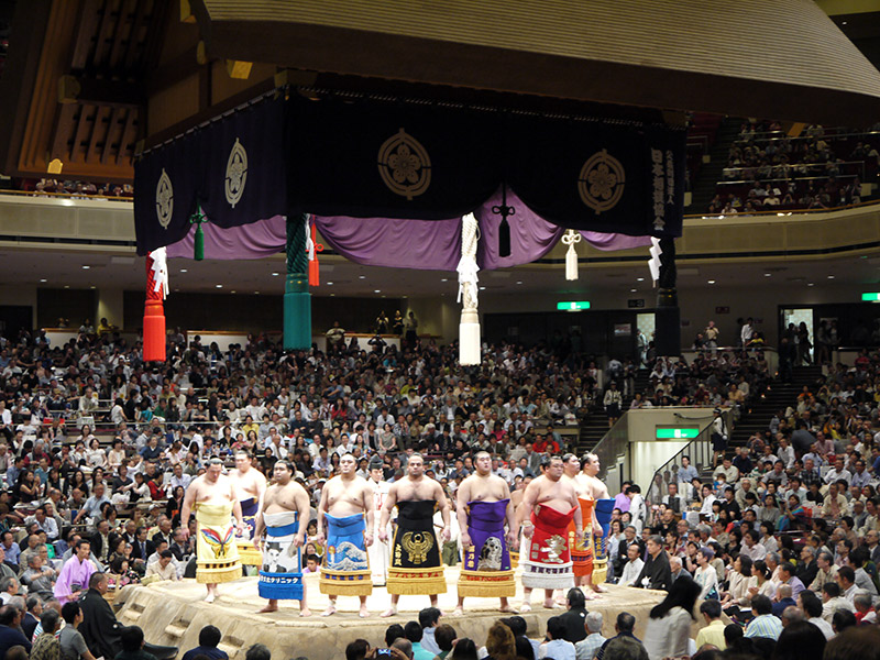 circle of sumo wrestlers facing the crowd