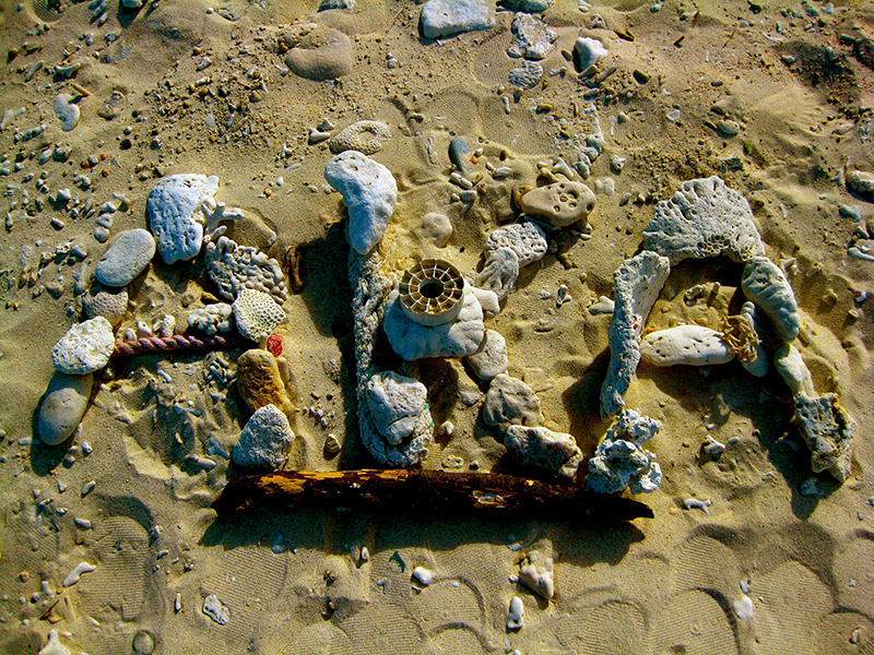 aka letters in sand formed with seashells and beach paraphernalia