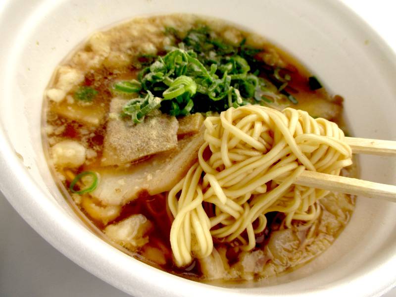 plastic bowl ramen closeup thin noodles red broth