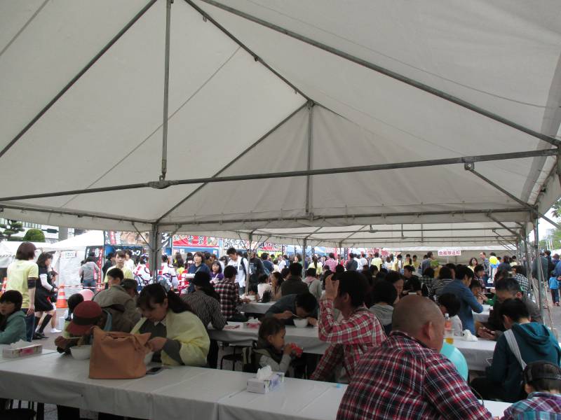 people eating ramen inside a tent