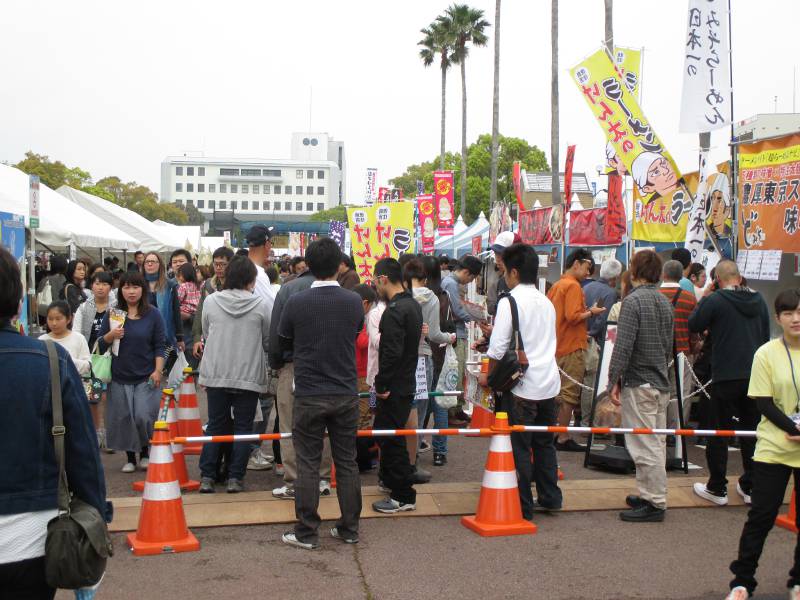 people stnading in line for food japan orange cones