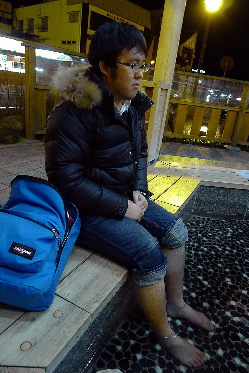 man in a foot onsen looking despondent