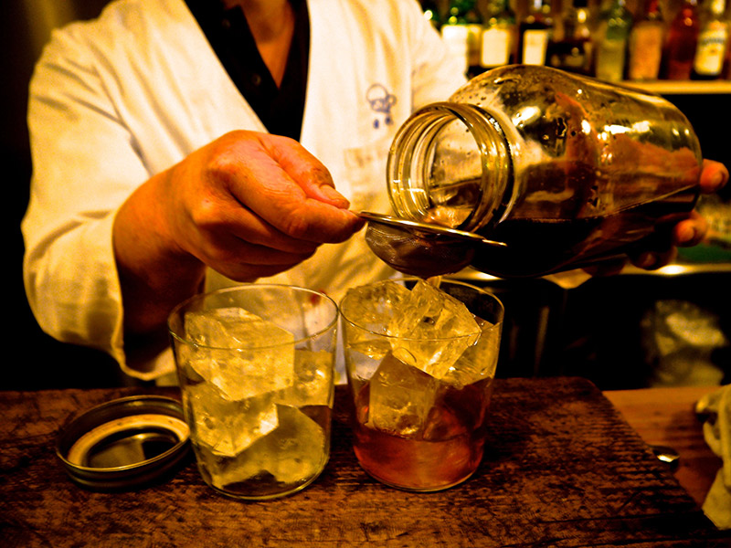 mixed drinks poured out of jar through strainer