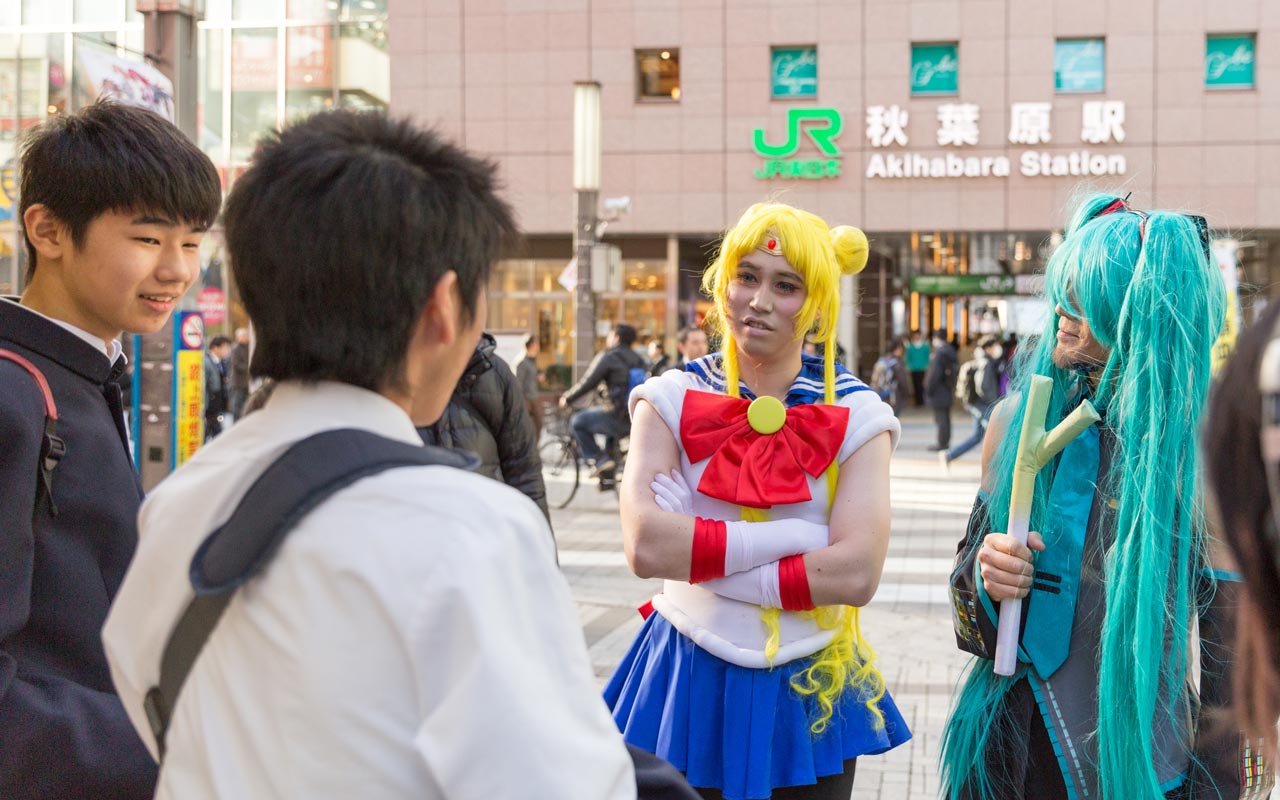 two men in cosplay talking to high schoolers in akihabara
