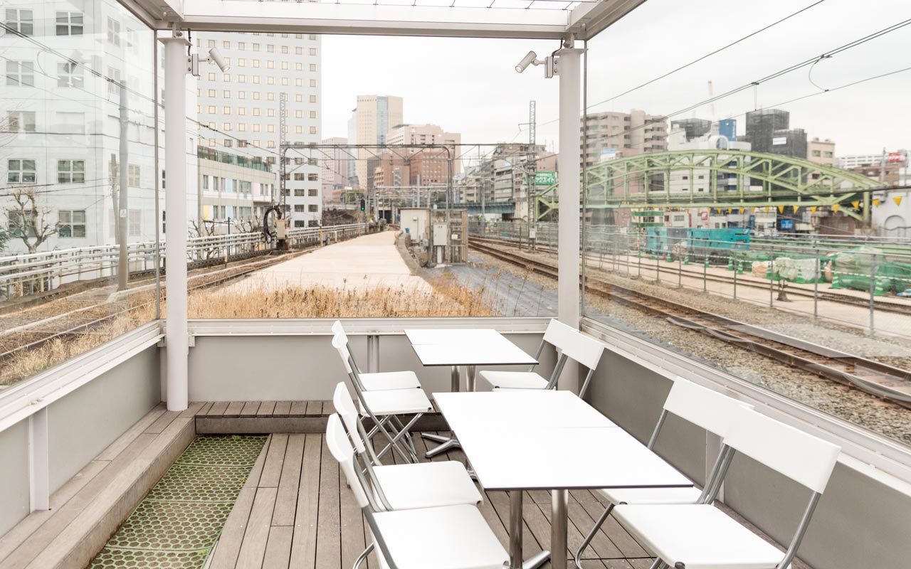 tables and chairs in between train tracks on maach ecute observation deck