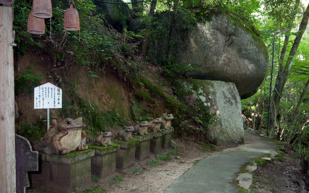 large frog statues on pedestals in forest