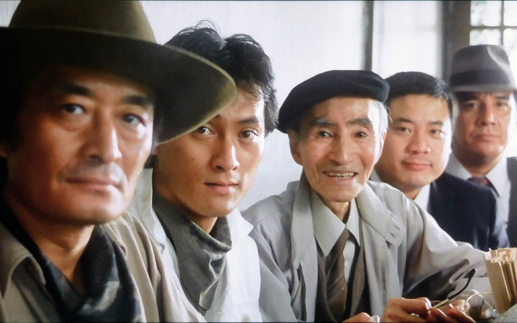 still from the movie tampopo showing a close up of five men in a row with varying facial expressions